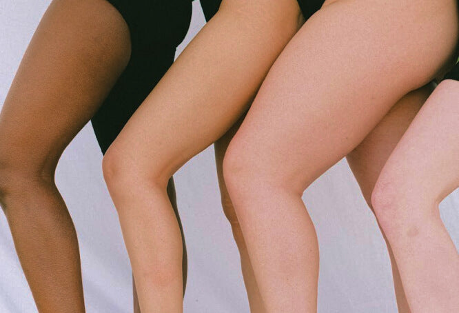 Photo de trois jambes de femmes alignées, montrant différentes carnations de peau, mettant en avant la diversité corporelle.
