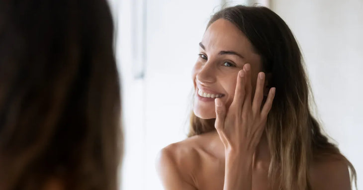 Femme souriante devant un miroir appliquant un soin hydratant sur une peau sèche - routine visage naturelle et bien-être
