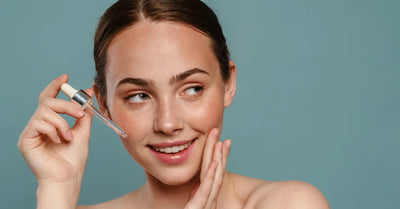 Femme souriante appliquant une huile visage naturelle anti-rides avec une pipette sur peau nue