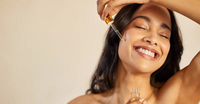 Femme souriante appliquant un sérum à la vitamine E sur le visage pour une peau éclatante et hydratée