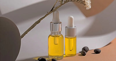 Deux flacons d’huile de jojoba visage pure avec pipette, posés sur fond naturel, entourés de graines de jojoba et d’une fleur séchée
