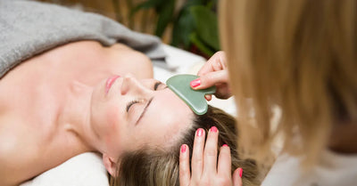 Application d’une pierre de massage visage en jade sur le front d’une femme pendant un soin – technique naturelle pour sculpter le visage