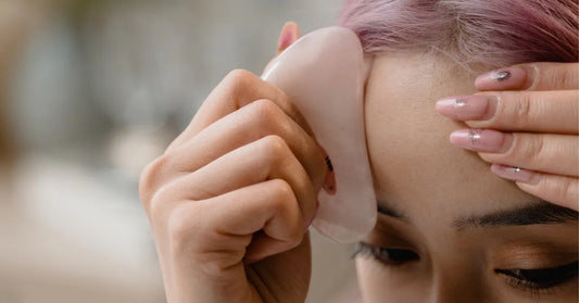 Utilisation du gua sha sur le front avec un outil en quartz rose pour massage visage